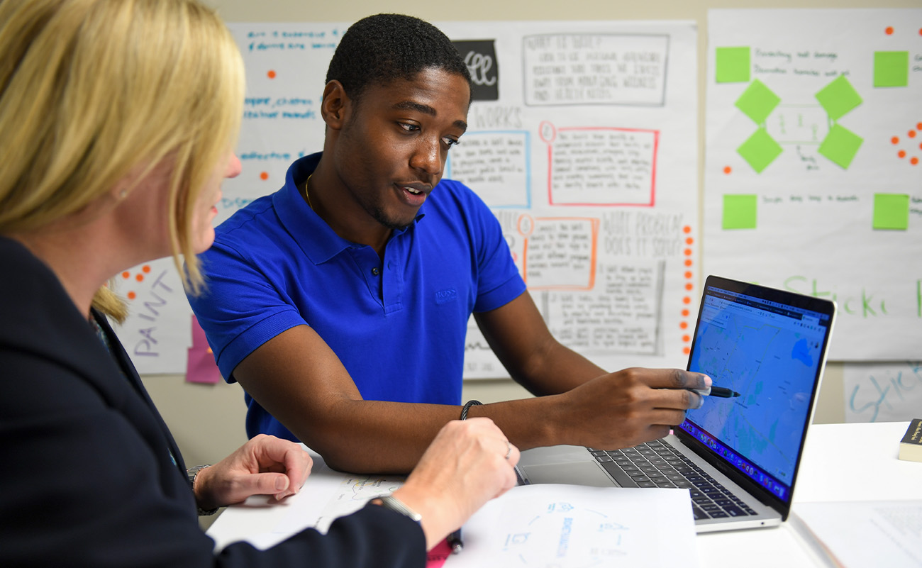 student and professor looking at laptop