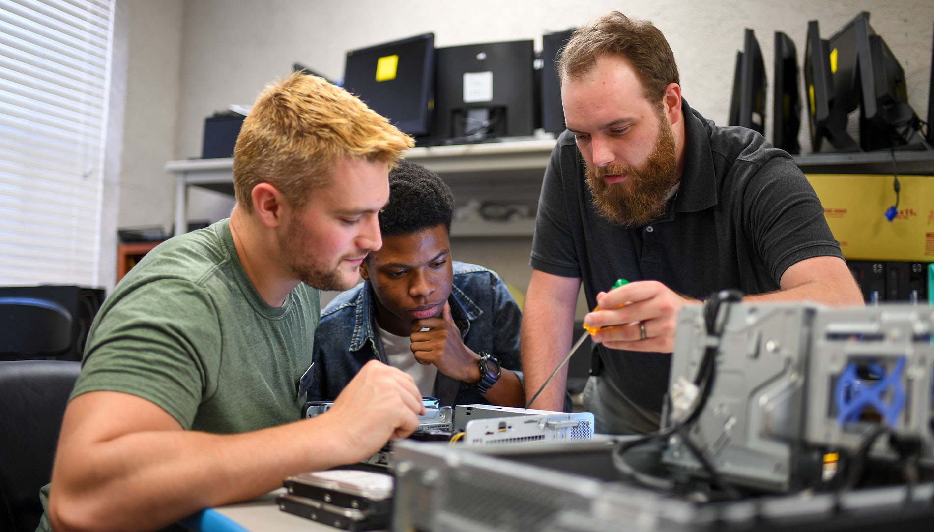 two students watching a staff member work on computer